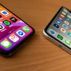 Dwa iPhone'y na drewnianym blacie, jeden z ikonami aplikacji, jakby przygotowany do jailbreak.