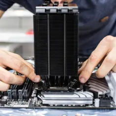 Dłonie montują duży, czarny radiator procesora na płycie głównej. To kluczowy element, by siw komputer działał sprawnie.