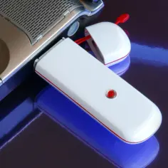 Mobilny internet LTE biurowy dla firm: klawiatura laptopa i biały modem USB z czerwoną diodą.