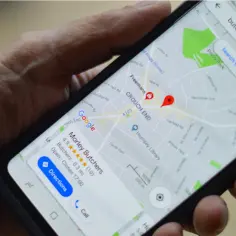 Dłoń trzyma smartfon z widokiem na mapy Google offline. Na ekranie zaznaczony jest sklep "Morley Butchers" w dzielnicy Crouch End.