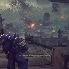 Space marine w niebieskiej zbroi obserwuje pole bitwy z wybuchami i ostrzałem.
