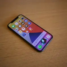iPhone z aktywną Siri na drewnianym blacie.