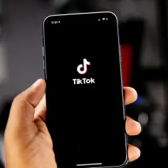 Dłoń trzyma smartfon z czarnym ekranem i logo TikToka. Czyżby awaria TikToka?