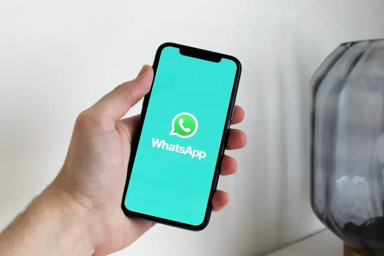 Dłoń trzyma smartfon z ekranem pokazującym logo WhatsApp. Gotowy do pobrania i instalacja aplikacji.
