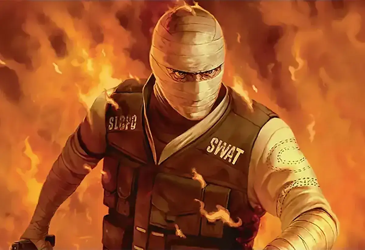 Joshua Graham, owinięty bandażami, w kamizelce SWAT, stoi na tle płomieni.
